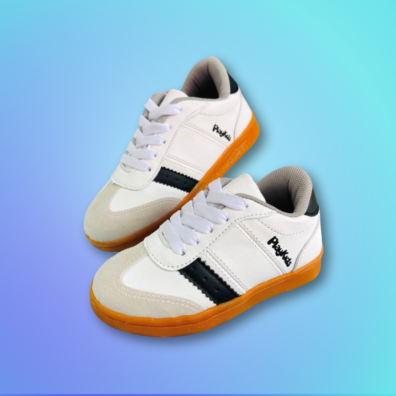 Tenis para Niña Estos elegantes tenis para niña presentan un diseño clásico en blanco con detalles en negro, complementados por una suela en tono caramelo que ofrece un toque distintivo.